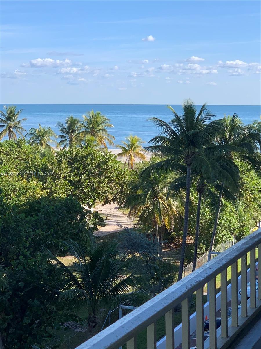 A balcony view overlooks palm trees, a sandy path, and the ocean under a blue sky — 177 Ocean Lane Dr # 512, Key Biscayne FL 33149, KEY BISCAYNE, FL