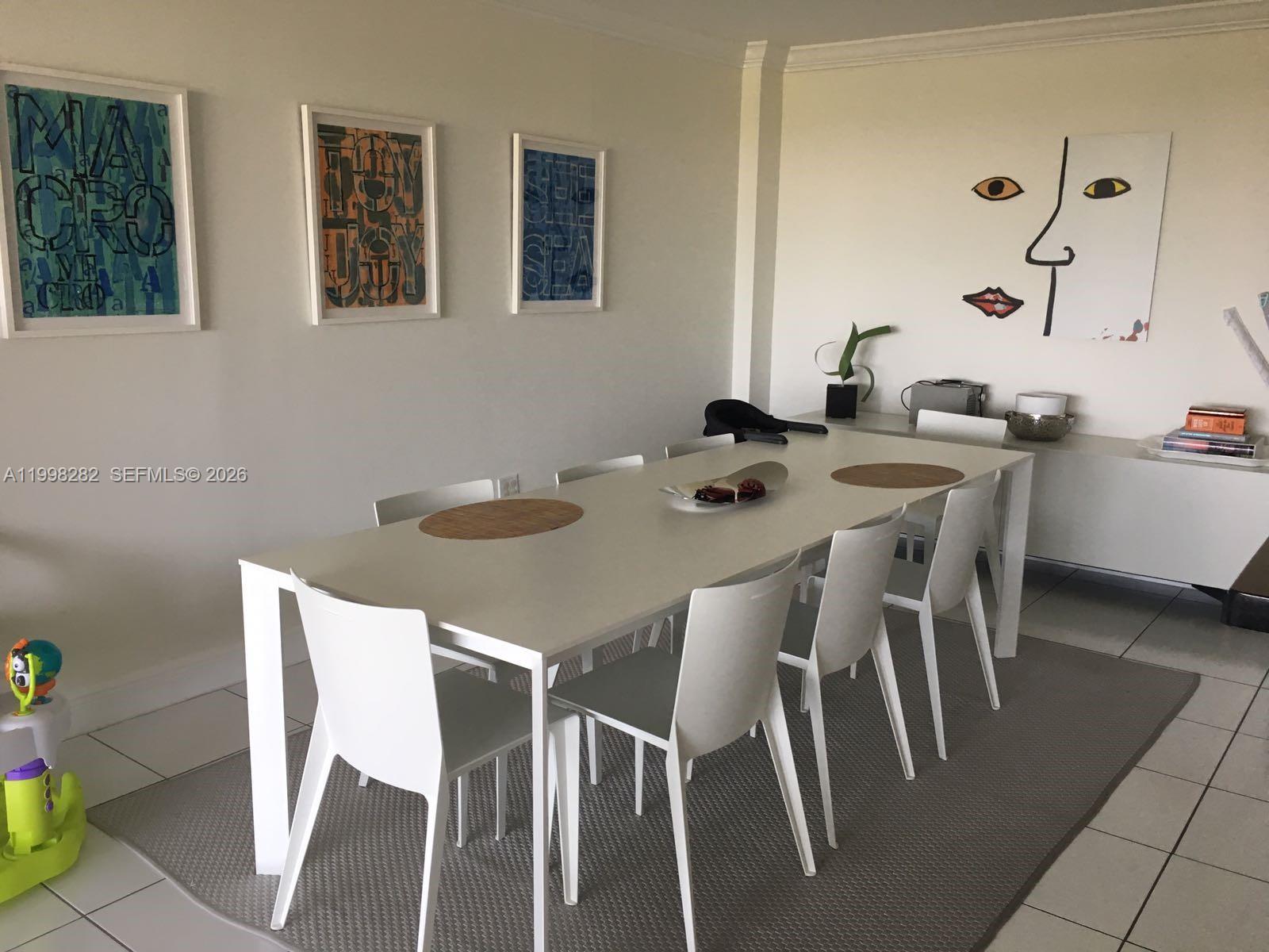 A dining room features a white table with six chairs on a gray area rug — 177 Ocean Lane Dr # 512, Key Biscayne FL 33149, KEY BISCAYNE, FL