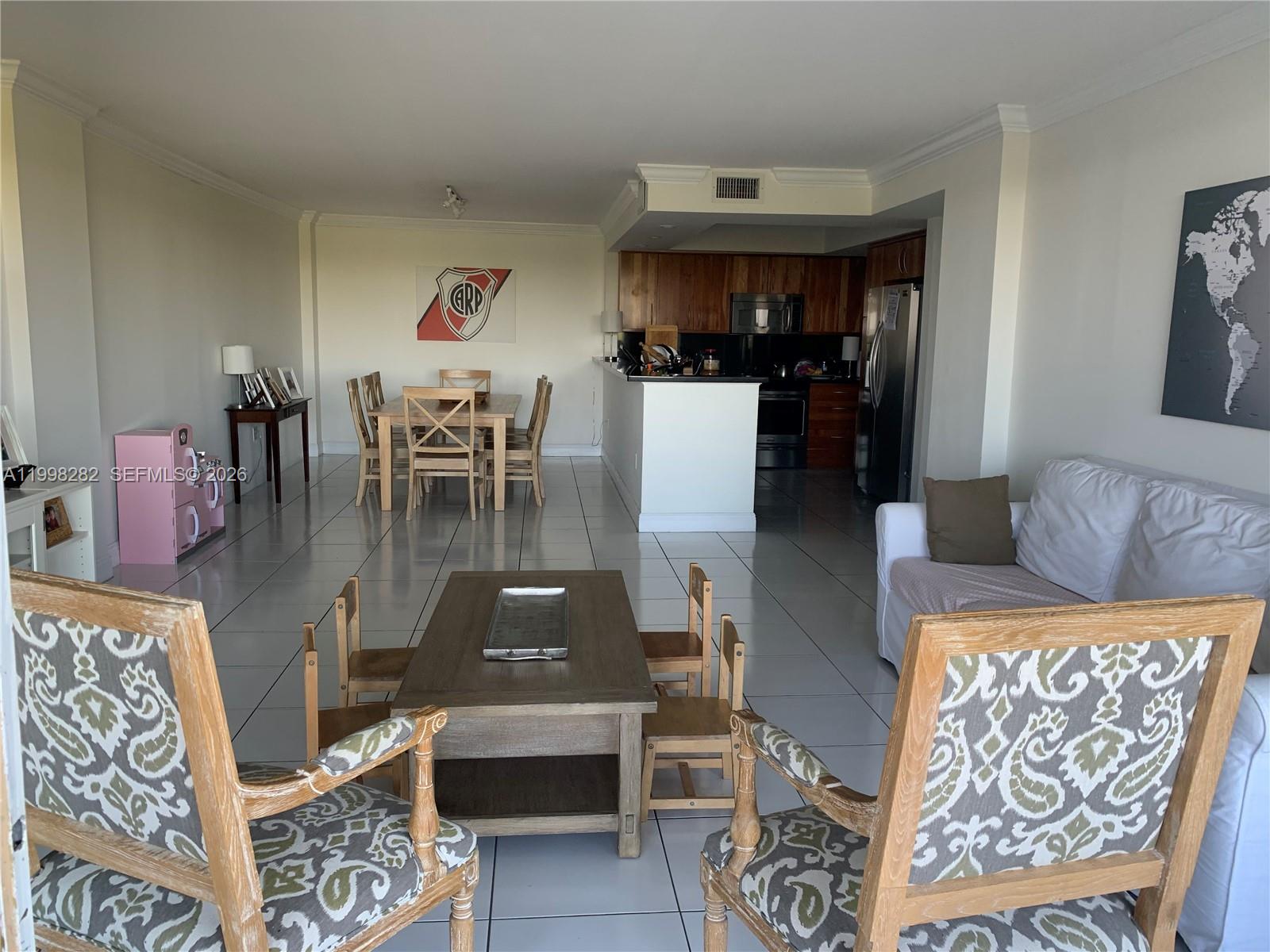 An open-concept living and dining area features tile flooring, a kitchen island, and wooden furniture — 177 Ocean Lane Dr # 512, Key Biscayne FL 33149, KEY BISCAYNE, FL