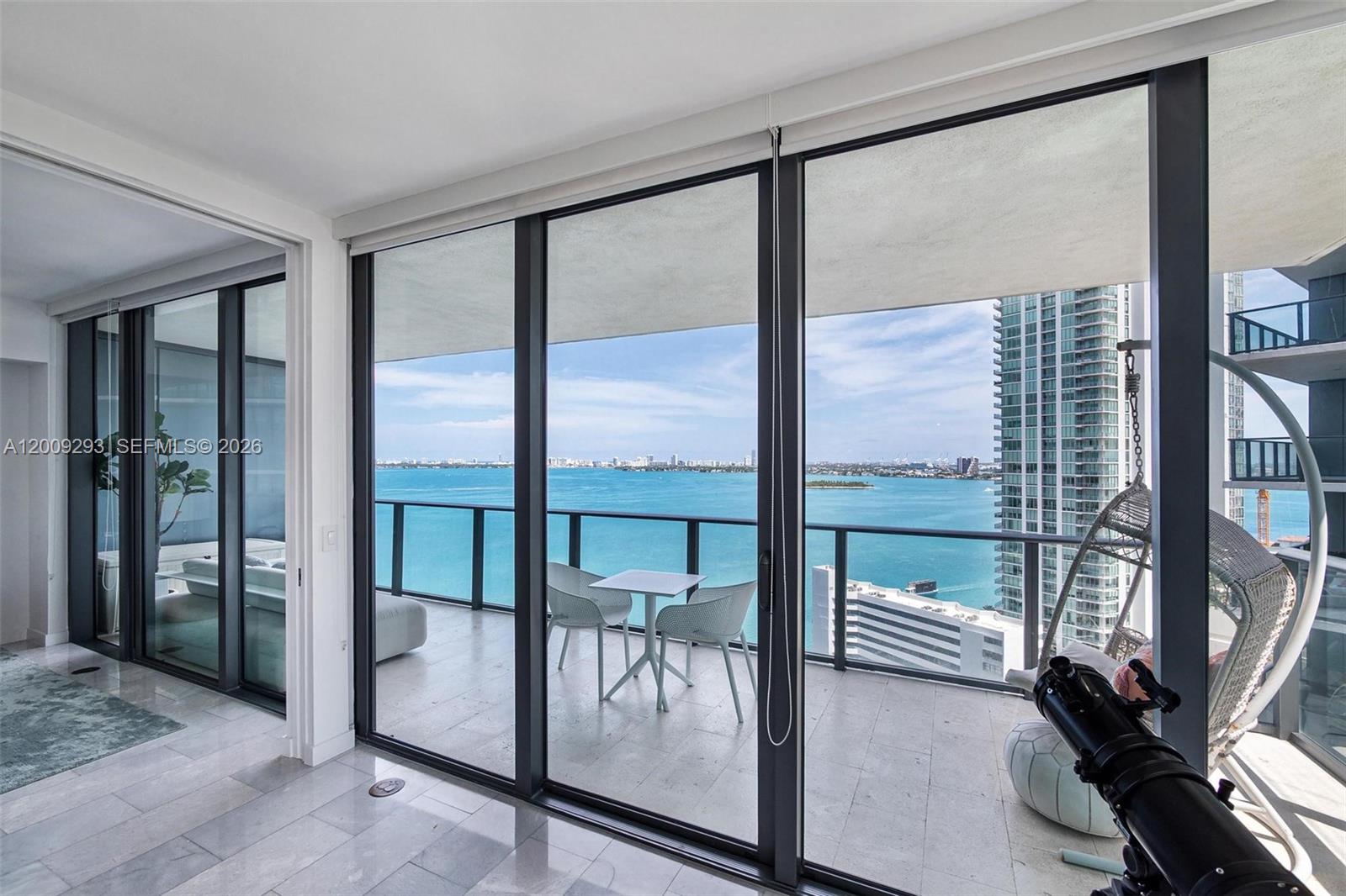A balcony with a table and chairs overlooks the ocean and city skyline — 650 NE 32nd St # 2101, Miami FL 33137, MIAMI, FL