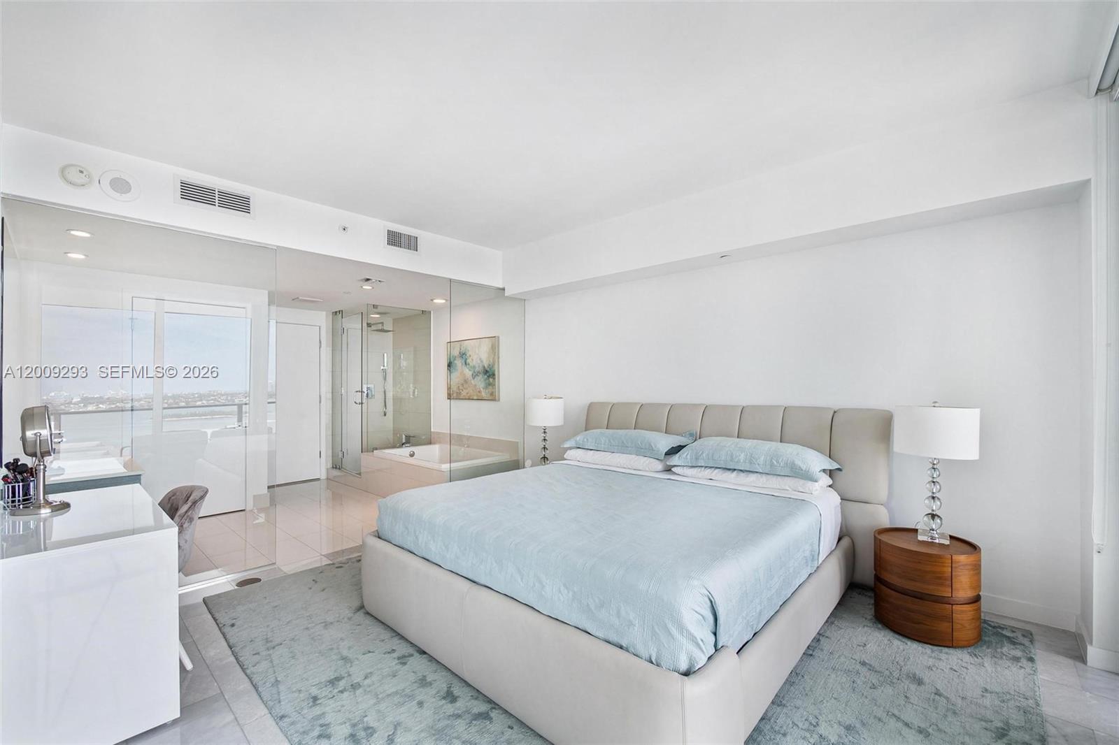 A modern bedroom features a light blue bed, glass-walled bathroom, and a view of water — 650 NE 32nd St # 2101, Miami FL 33137, MIAMI, FL