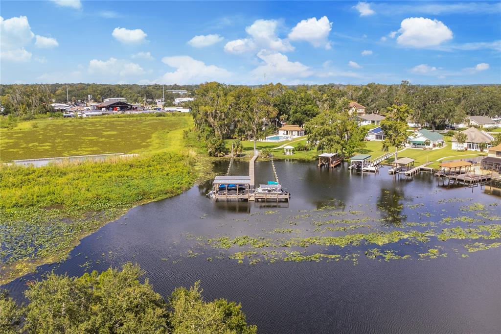 An aerial view shows a boat dock on a lake surrounded by houses and vegetation — 947 BELLE OAK DRIVE, LEESBURG, FL