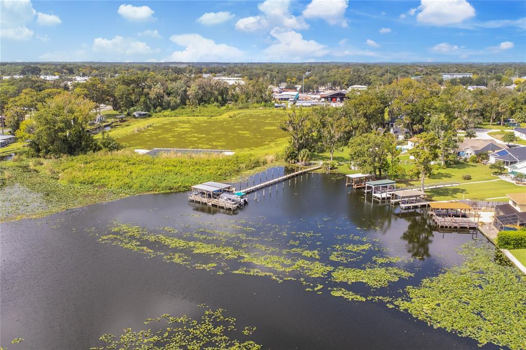 An aerial view of a lake with a long wooden dock and several boat slips — 947 BELLE OAK DRIVE, LEESBURG, FL