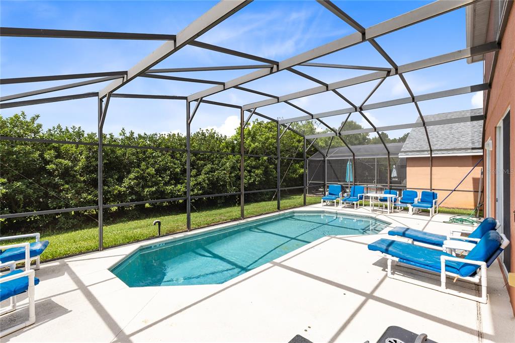A screened-in swimming pool with patio furniture sits on a concrete deck beside a house — 180 HIDEAWAY BEACH LANE, KISSIMMEE, FL