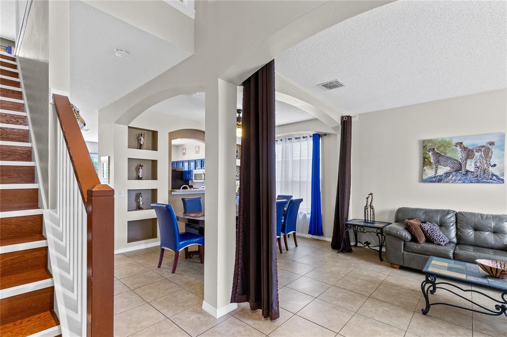 A view from a staircase looking into a living room and dining area with tile — 180 HIDEAWAY BEACH LANE, KISSIMMEE, FL