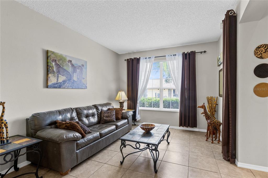 A living room features a leather sofa, a tiled coffee table, and animal-themed decor — 180 HIDEAWAY BEACH LANE, KISSIMMEE, FL