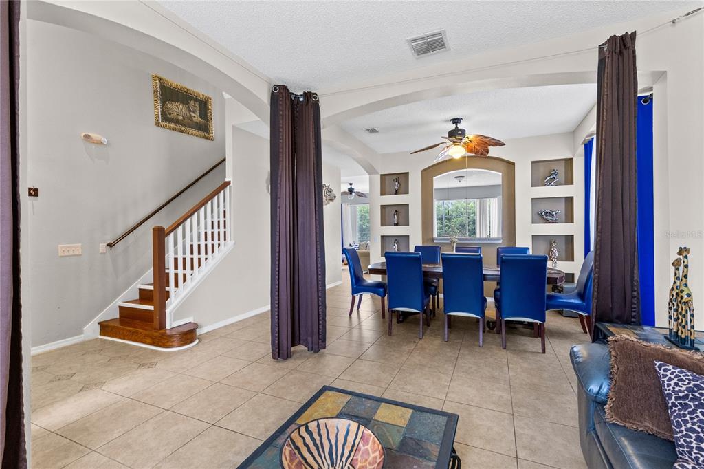 A dining room with blue chairs, tile flooring, and a staircase leading to the upper level — 180 HIDEAWAY BEACH LANE, KISSIMMEE, FL