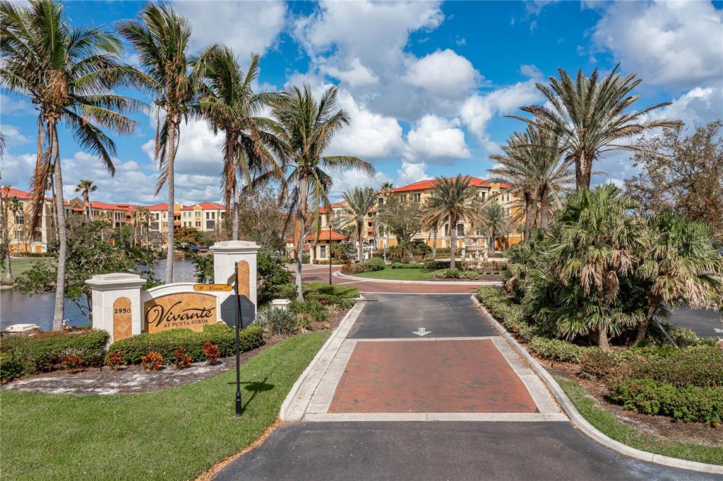 The entrance to a residential community features a stone sign, palm trees, and paved roads — 85 VIVANTE BOULEVARD UNIT 8542, PUNTA GORDA, FL