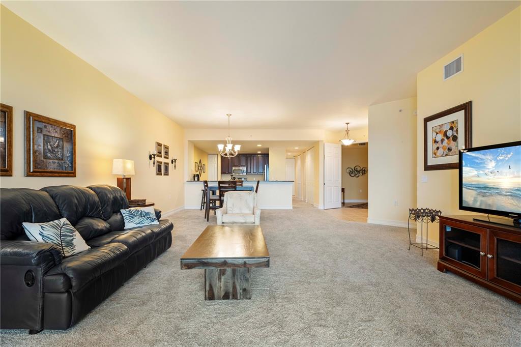A living room with a black leather sofa, coffee table, and open kitchen in background — 85 VIVANTE BOULEVARD UNIT 8542, PUNTA GORDA, FL