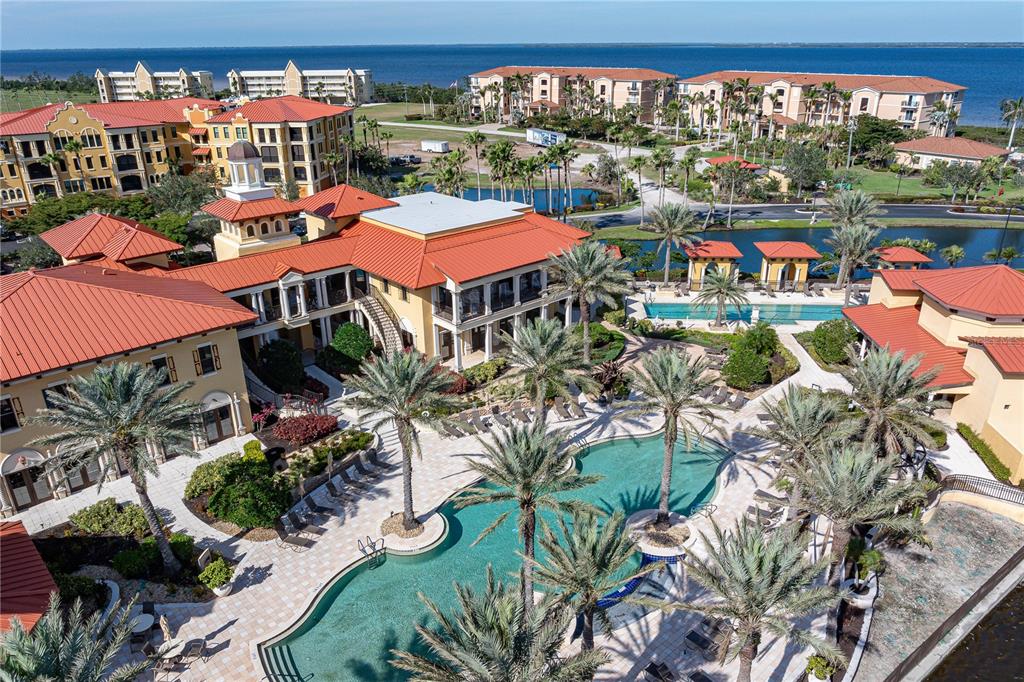 An aerial view shows a resort-style pool area surrounded by multi-story buildings with orange roofs — 85 VIVANTE BOULEVARD UNIT 8542, PUNTA GORDA, FL