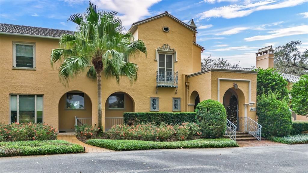 A two-story yellow stucco house features arched entryways, a small balcony, and a palm tree — 2300 N SCENIC HIGHWAY UNIT 37E, LAKE WALES, FL