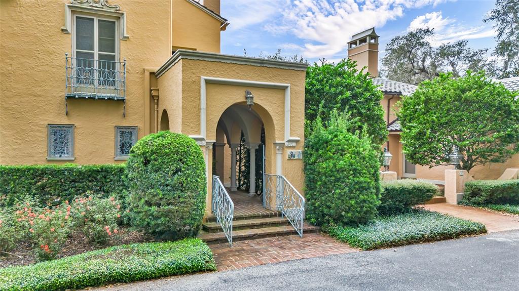 A yellow stucco building features an arched entryway with a brick path and metal railings — 2300 N SCENIC HIGHWAY UNIT 37E, LAKE WALES, FL