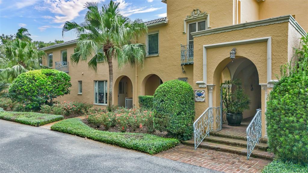 A yellow stucco building features arched entryways, a brick walkway, and lush landscaping — 2300 N SCENIC HIGHWAY UNIT 37E, LAKE WALES, FL