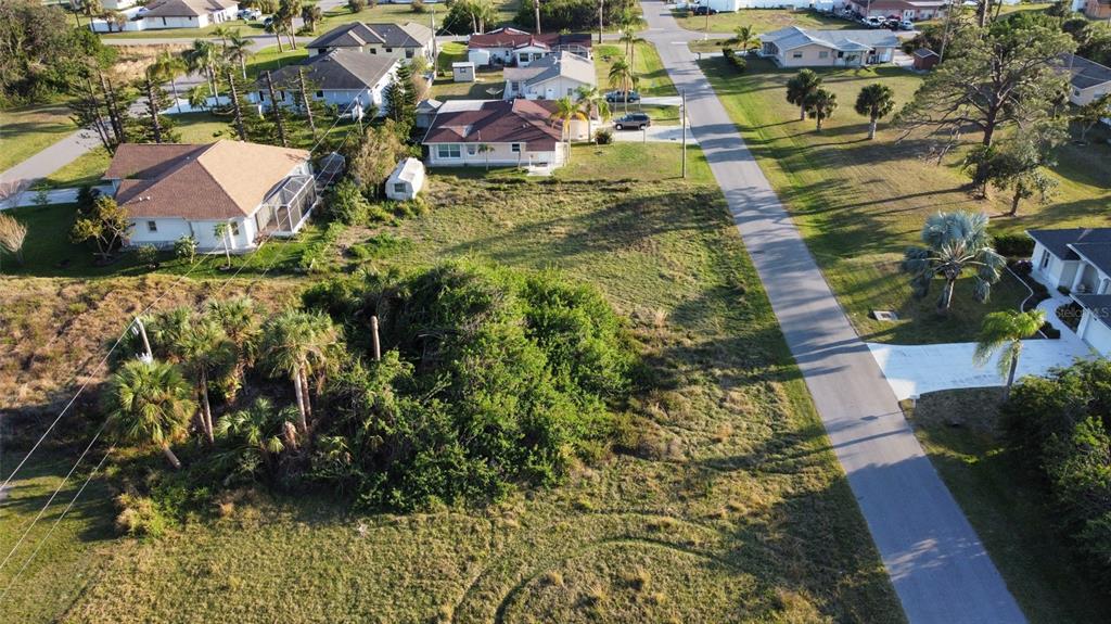An aerial view shows a vacant, grassy lot surrounded by residential houses and palm trees — SAN REMO AVENUE, NORTH PORT, FL