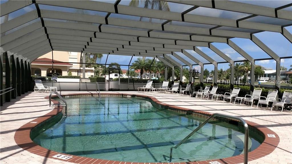 A screened-in swimming pool with a brick border and lounge chairs on a patio — 1 COLONY POINT DRIVE UNIT A5, PUNTA GORDA, FL