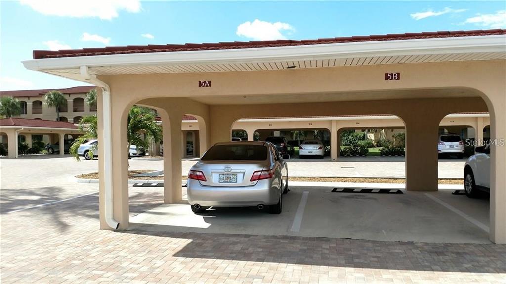 A covered parking carport with numbered spaces sits in front of a residential building — 1 COLONY POINT DRIVE UNIT A5, PUNTA GORDA, FL