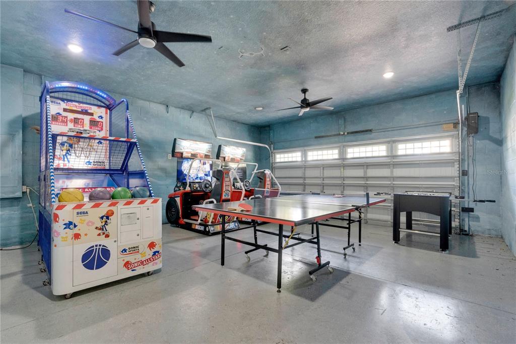 A garage converted into a game room with arcade machines, a ping pong table, and foosball — 7657 WILMINGTON LOOP, KISSIMMEE, FL