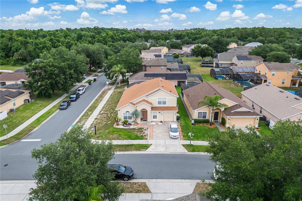An aerial view shows a suburban neighborhood with houses, driveways, and surrounding trees — 1228 SANDY RIDGE DRIVE, DAVENPORT, FL