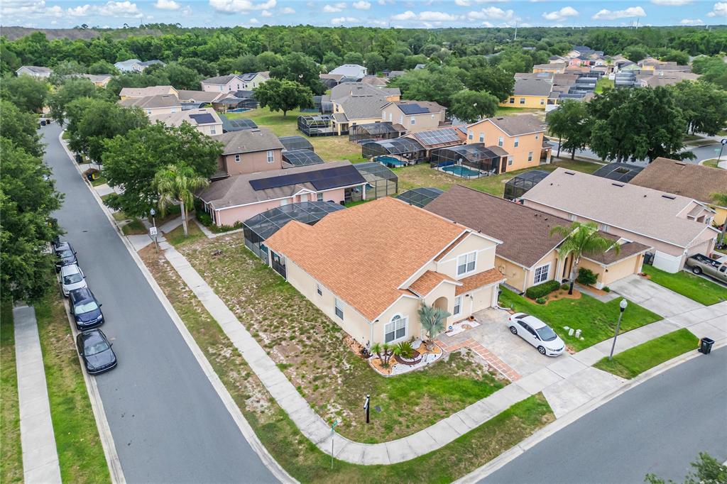 An aerial view shows a suburban neighborhood with houses, swimming pools, and parked cars — 1228 SANDY RIDGE DRIVE, DAVENPORT, FL