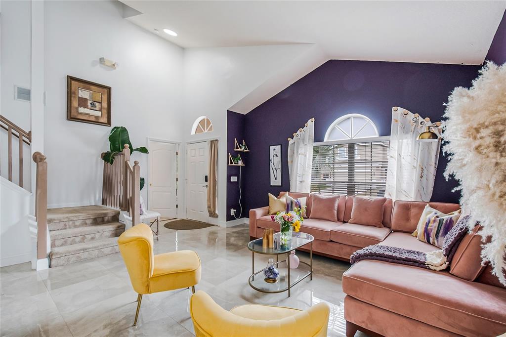 A living room features a vaulted ceiling, purple accent wall, pink sectional, and yellow chairs — 1228 SANDY RIDGE DRIVE, DAVENPORT, FL