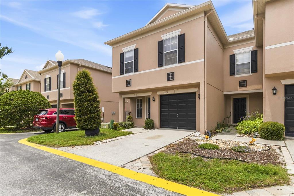 A two-story tan townhouse with a black garage door and a concrete driveway — 2825 CLIFFE COURT, OVIEDO, FL