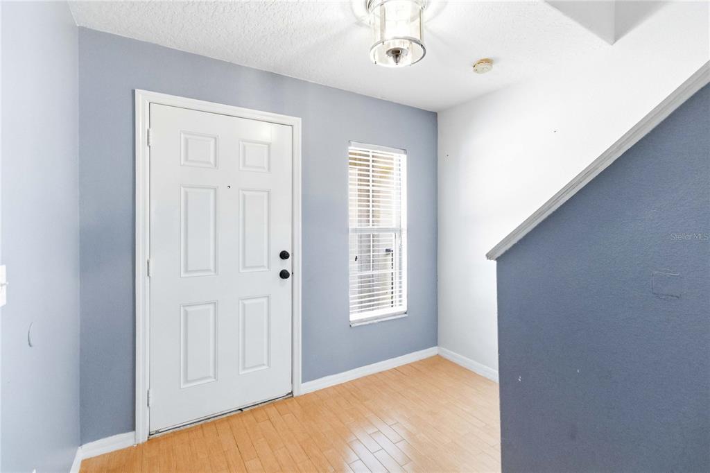 An entryway features a white front door, a window with blinds, and light wood flooring — 2825 CLIFFE COURT, OVIEDO, FL
