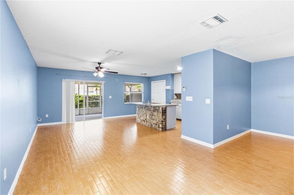 An open-concept living and kitchen area features light wood flooring and a tiled breakfast bar — 2825 CLIFFE COURT, OVIEDO, FL