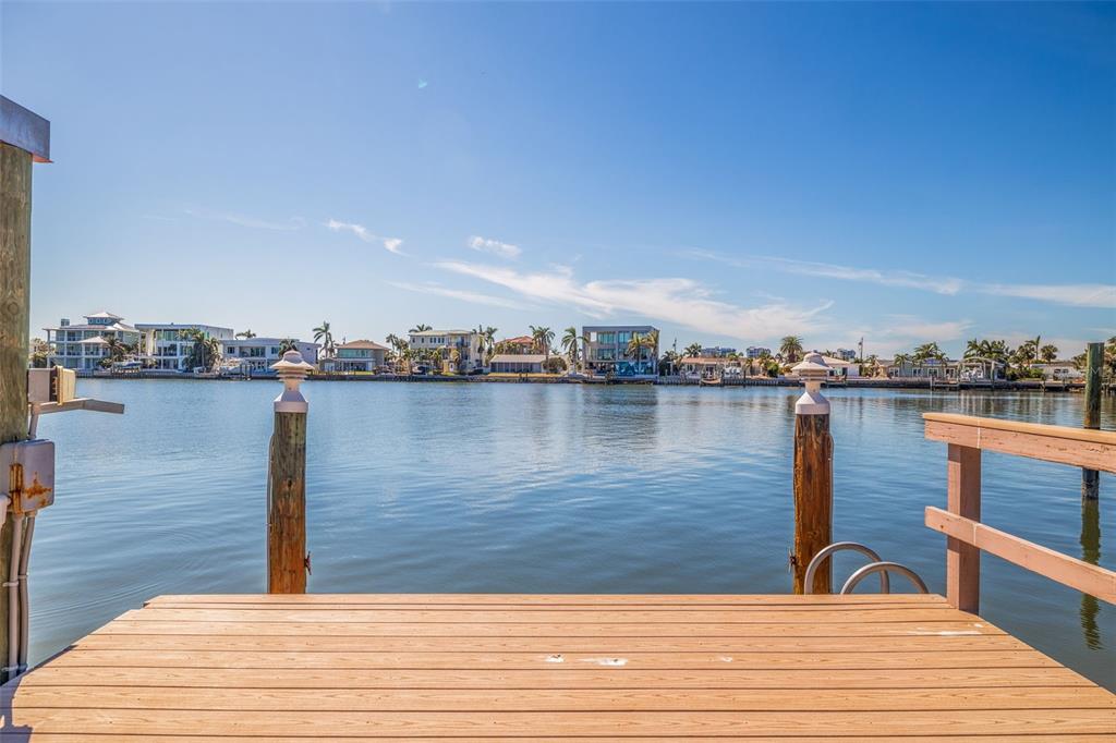 A wooden boat dock overlooks a calm waterway with residential homes along the distant shore — 7874 9TH AVENUE S, ST PETERSBURG, FL