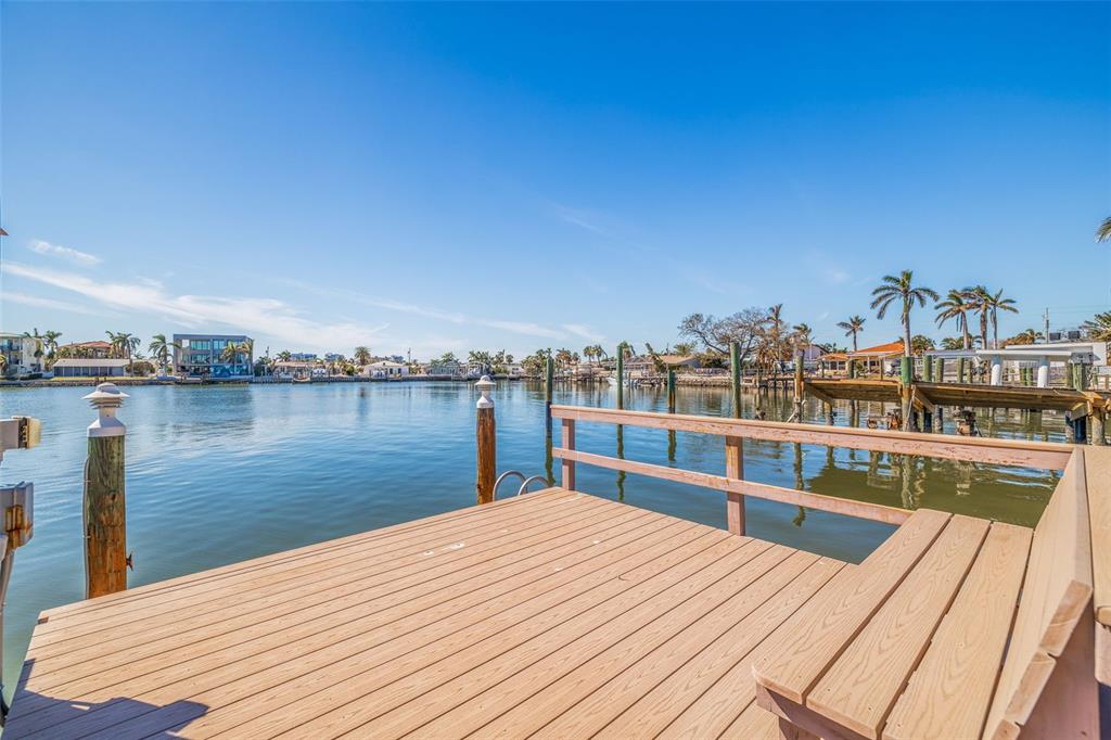 A wooden dock with a built-in bench overlooks a calm canal under a clear sky — 7874 9TH AVENUE S, ST PETERSBURG, FL