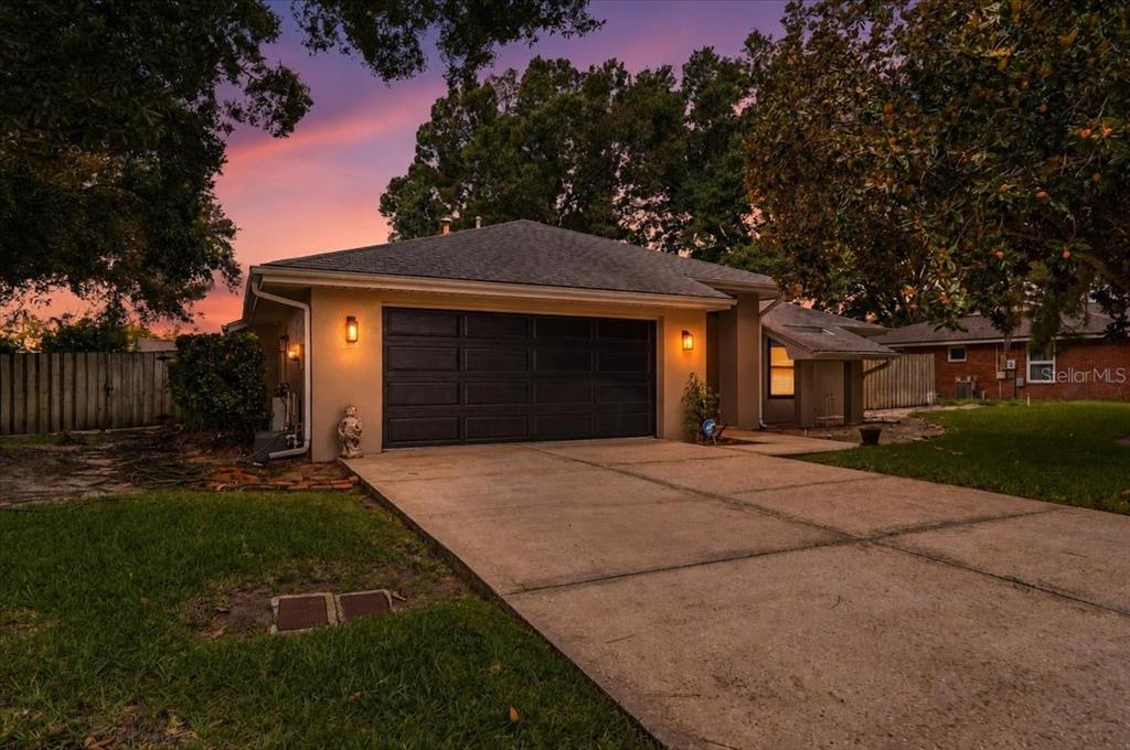 A single-story house with a two-car garage and a concrete driveway at sunset — 238 COLLEGE GROVE CIRCLE NE, WINTER HAVEN, FL