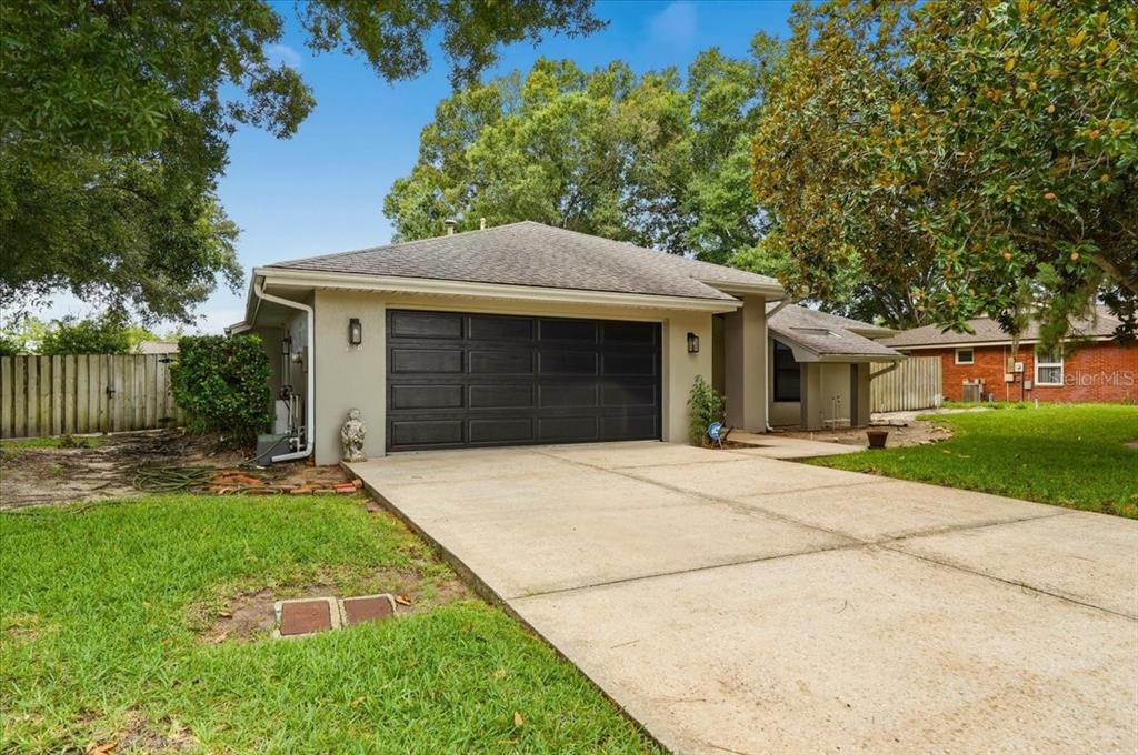 A single-story house with a concrete driveway and a dark-colored two-car garage door — 238 COLLEGE GROVE CIRCLE NE, WINTER HAVEN, FL
