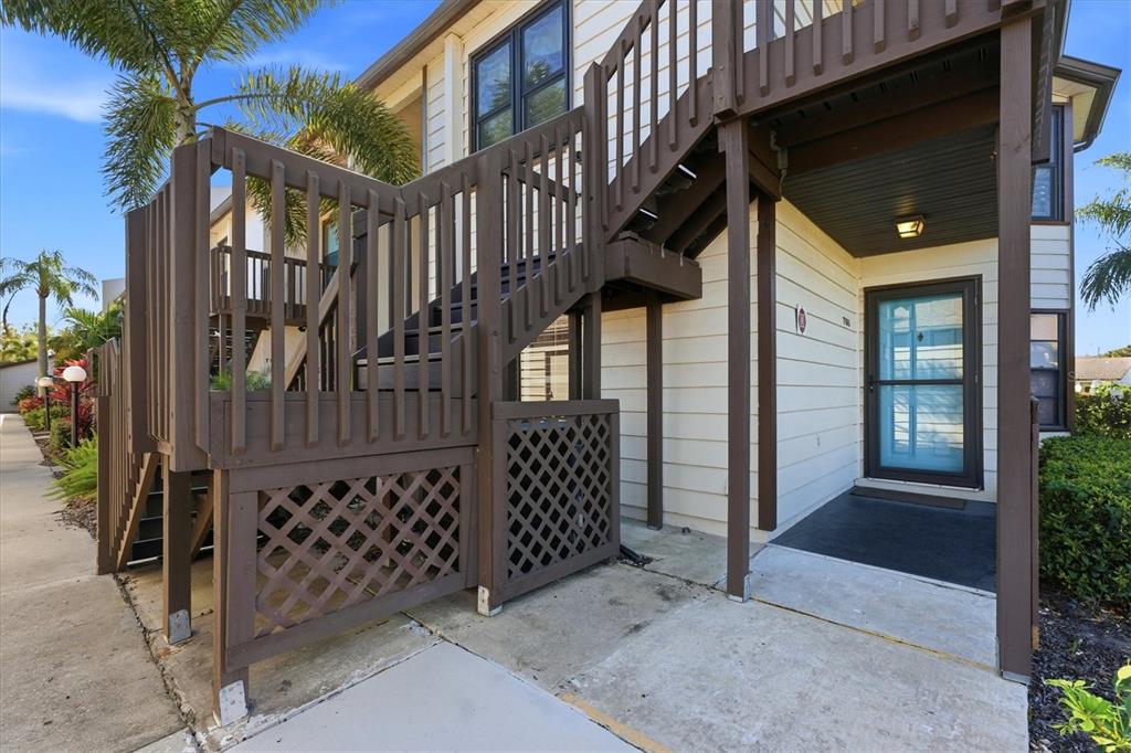 An exterior view of a multi-story building featuring a wooden staircase and a front entrance — 7165 28TH AVENUE W, BRADENTON, FL