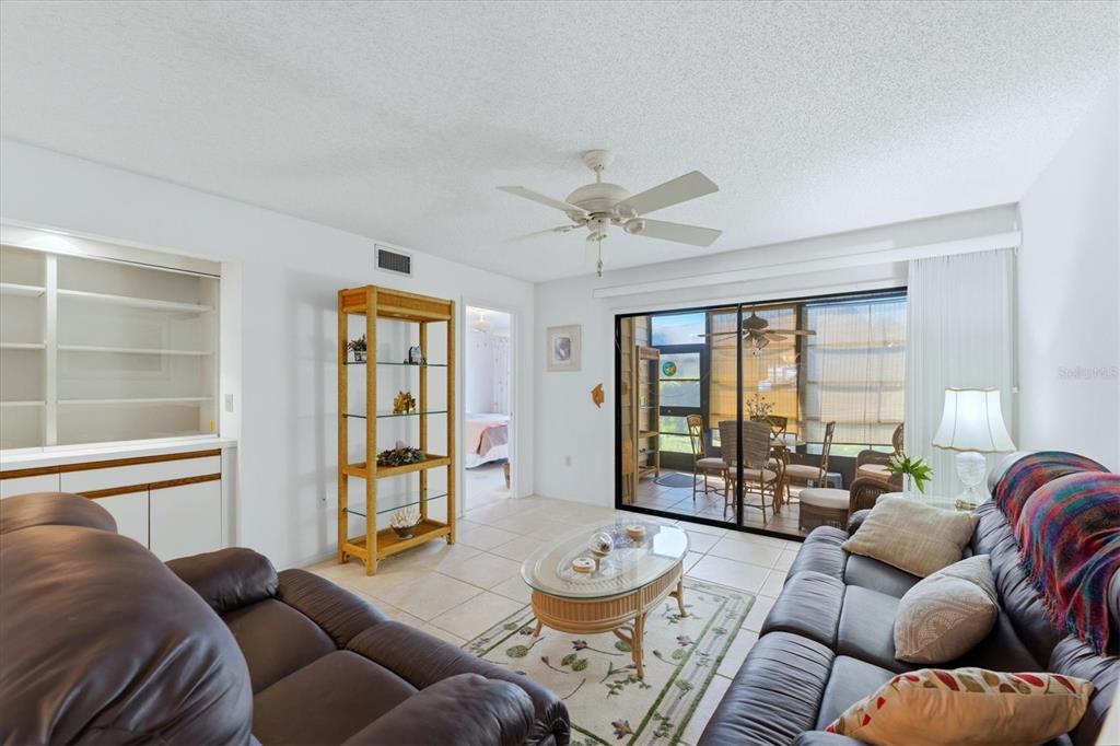 A living room with tile floors, two leather sofas, a glass coffee table, and a lanai — 7165 28TH AVENUE W, BRADENTON, FL