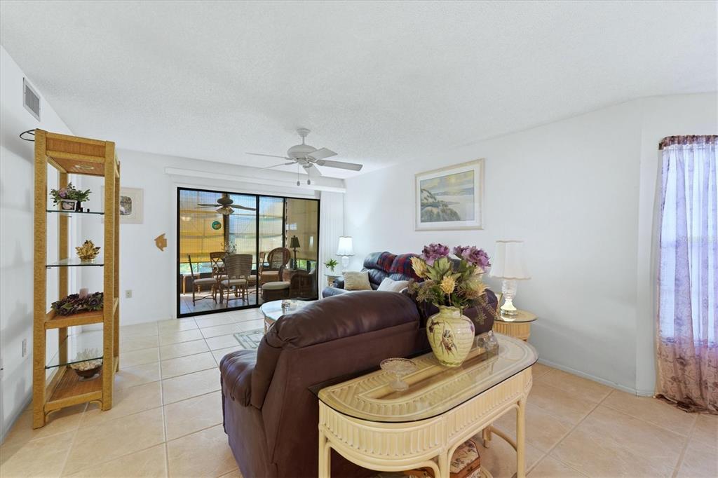 A living room features tile floors, a brown leather sofa, and a glass-topped console table — 7165 28TH AVENUE W, BRADENTON, FL