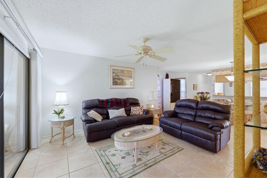 A living room features two dark leather sofas, a glass-topped coffee table, and tile flooring — 7165 28TH AVENUE W, BRADENTON, FL