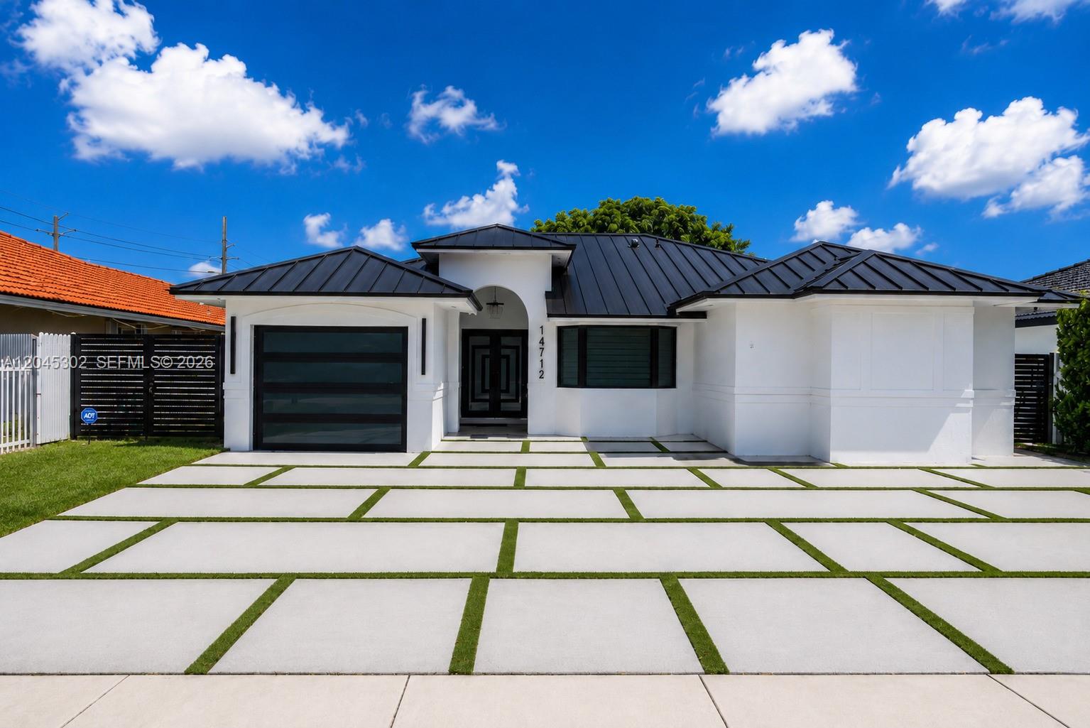 A modern white house with a black metal roof and a large concrete paver driveway — 14712 SW 176th Ter, Miami FL 33187, MIAMI, FL