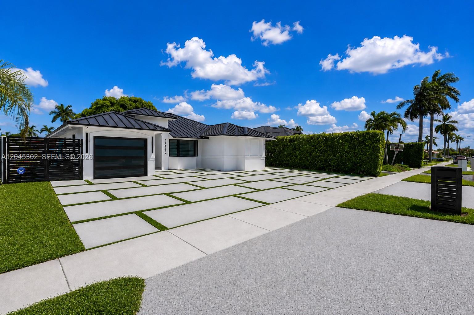 A modern white house features a black metal roof and a grid-patterned concrete driveway — 14712 SW 176th Ter, Miami FL 33187, MIAMI, FL