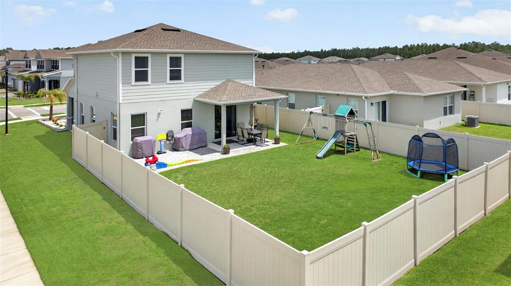 An aerial view of a two-story house with a fenced backyard, patio, and playground equipment — 381 CRESTWIND DRIVE, DAYTONA BEACH, FL