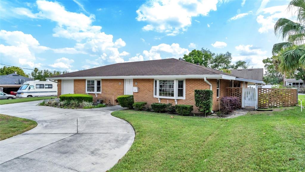 A single-story brick house features a large front lawn, a concrete driveway, and a roof — 901 WOODWARD STREET, LAKELAND, FL