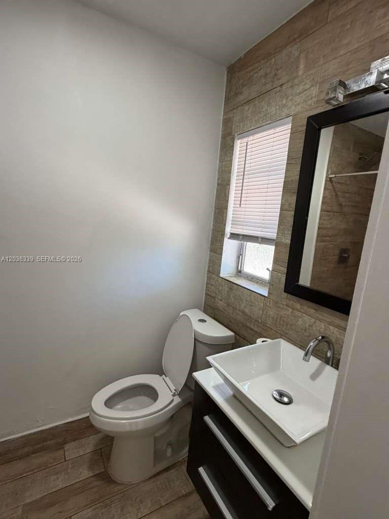 A bathroom features a vessel sink, a toilet, and wood-look tile on the wall — 5843 Harding St, Hollywood FL 33021, HOLLYWOOD, FL