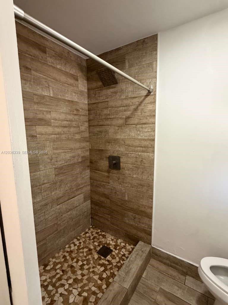 A walk-in shower features wood-look tile walls and a pebble-tiled floor — 5843 Harding St, Hollywood FL 33021, HOLLYWOOD, FL