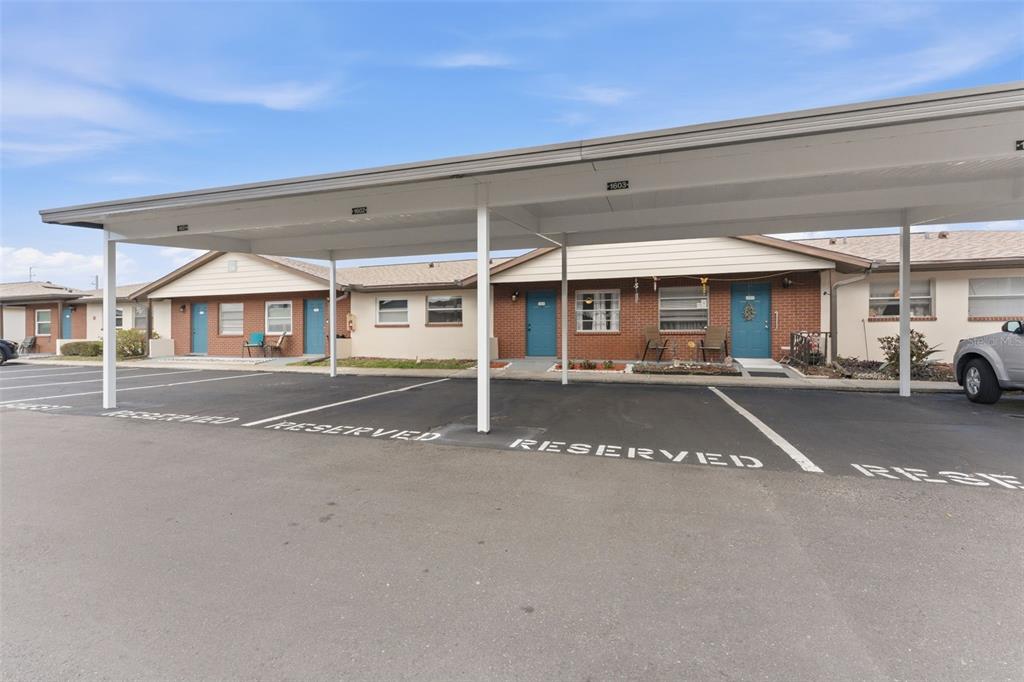A covered parking area sits in front of a single-story brick residential building — 24862 US HIGHWAY 19 N UNIT 1604, CLEARWATER, FL