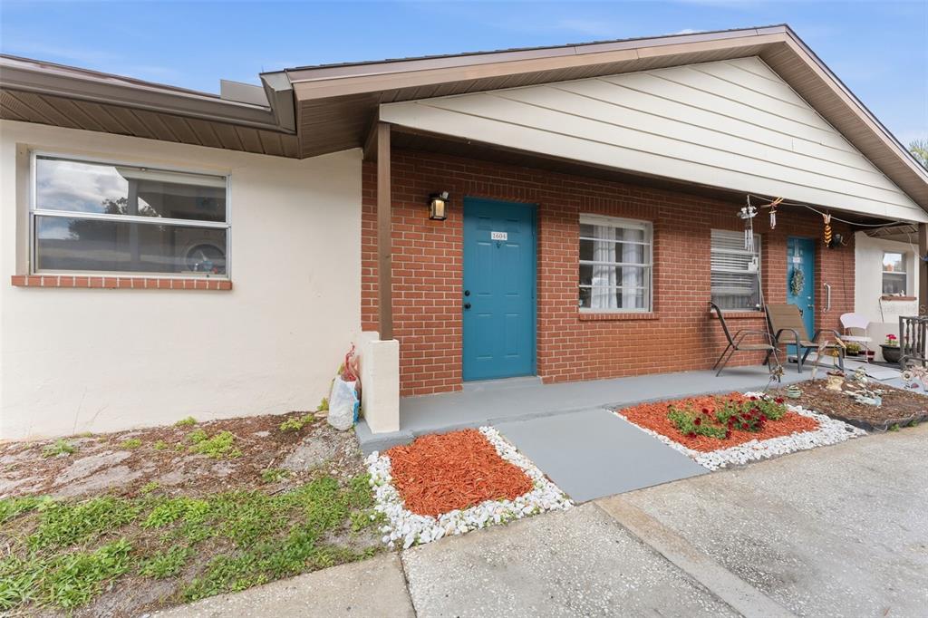 The exterior of a single-story brick and stucco building features a blue front door — 24862 US HIGHWAY 19 N UNIT 1604, CLEARWATER, FL