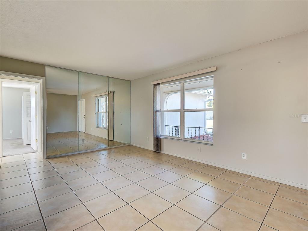 A room with beige tile flooring, a mirrored closet wall, and a large window — 1321 WASHINGTON DRIVE, ENGLEWOOD, FL