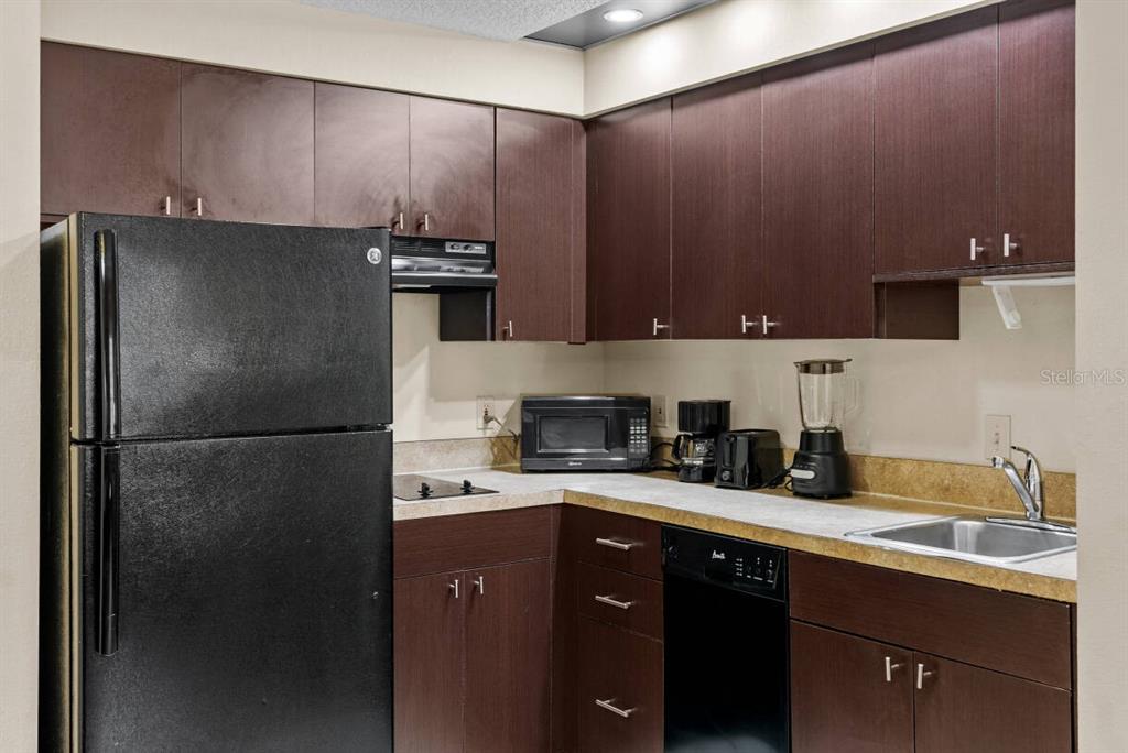A kitchen features dark wood cabinets, black appliances, and a light-colored countertop — 7601 CANADA AVENUE UNIT 221, ORLANDO, FL