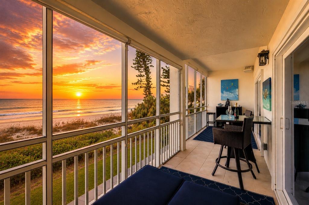 An aerial view shows a multi-story beachside apartment building near a sandy coastline — 7001 GULF OF MEXICO DRIVE UNIT 24, LONGBOAT KEY, FL