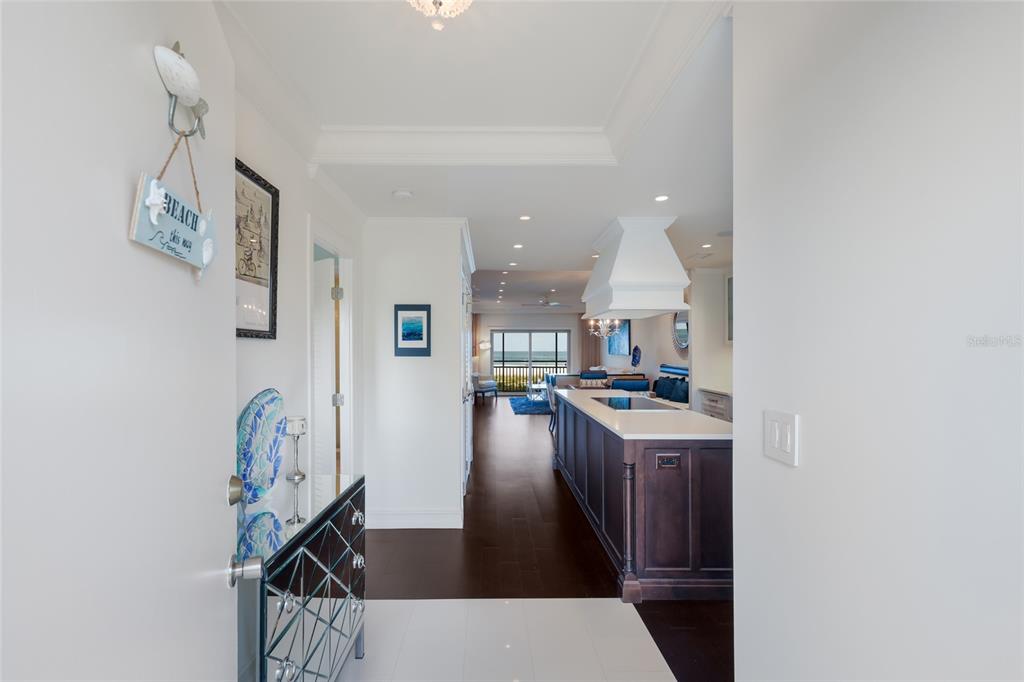 A screened-in balcony overlooks a beach at sunset with a small dining set and seating — 7001 GULF OF MEXICO DRIVE UNIT 24, LONGBOAT KEY, FL