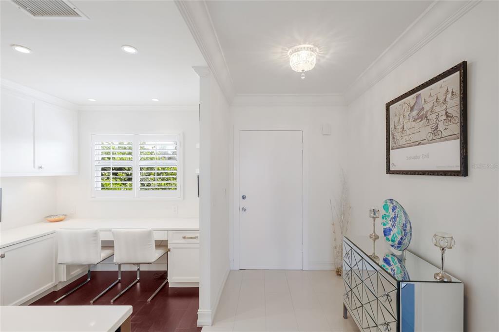 A view from an entryway looking into a kitchen with a dark island and living area — 7001 GULF OF MEXICO DRIVE UNIT 24, LONGBOAT KEY, FL