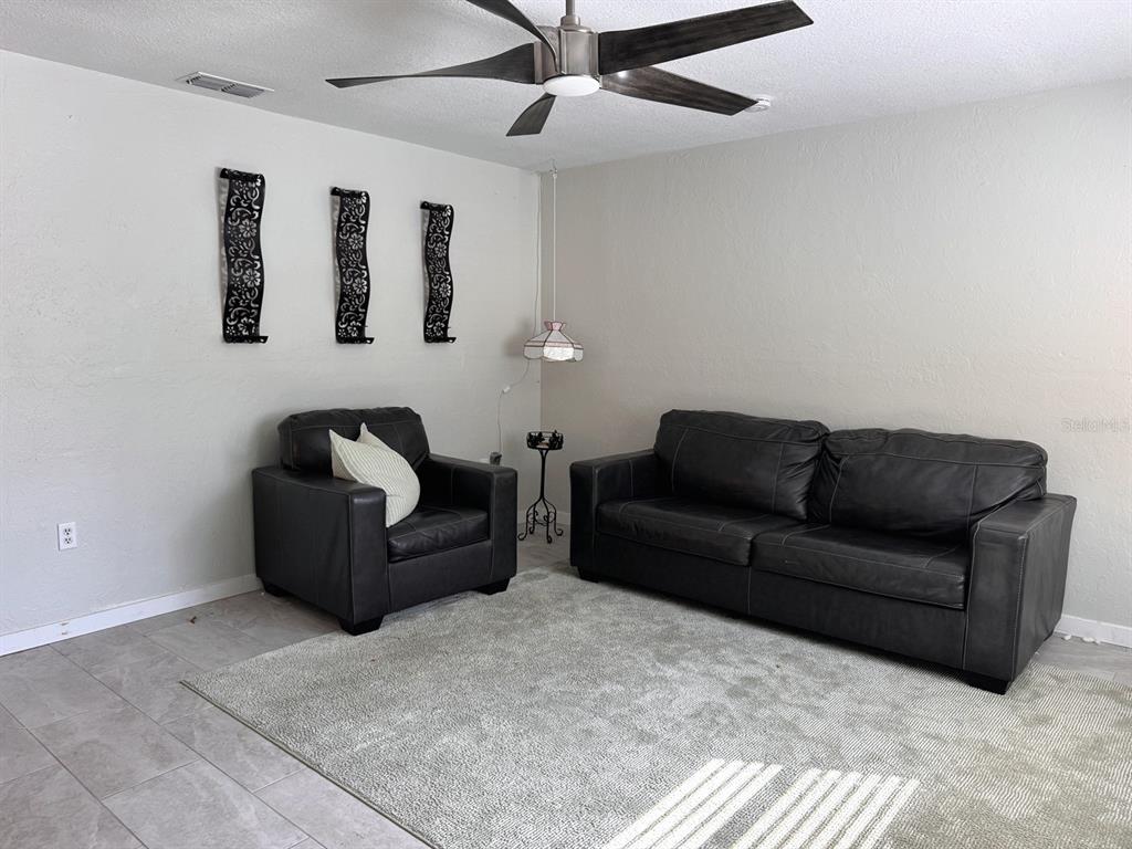 A living room features a black leather sofa and armchair on a gray area rug — 3414 NW 21ST DRIVE UNIT E4, GAINESVILLE, FL