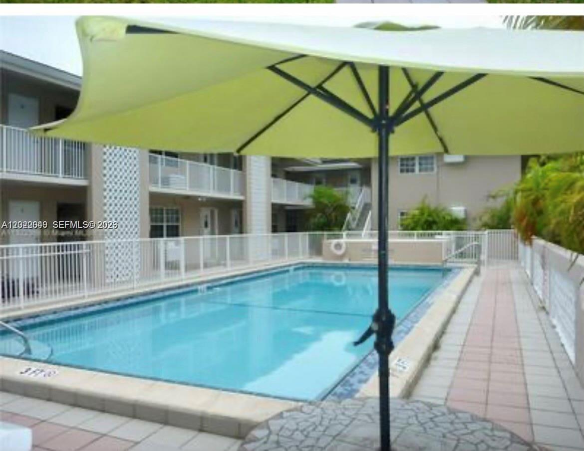 A rectangular swimming pool is situated in a courtyard surrounded by a multi-story apartment building — 6565 Santona St, Coral Gables FL 33146, CORAL GABLES, FL